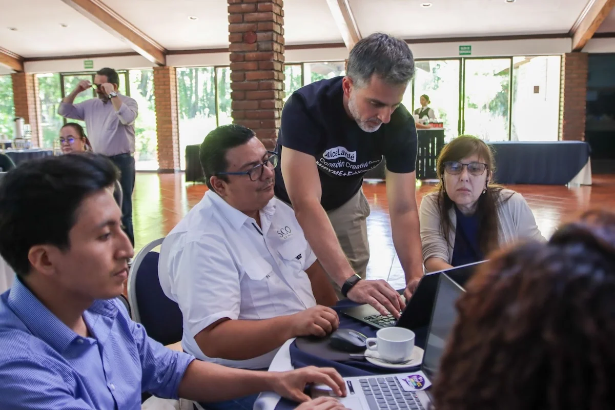 Julián Martínez, de Suricata Labs, acompaña a un grupo de asesores frente a un computador durante una sesión práctica del programa en El Salvador